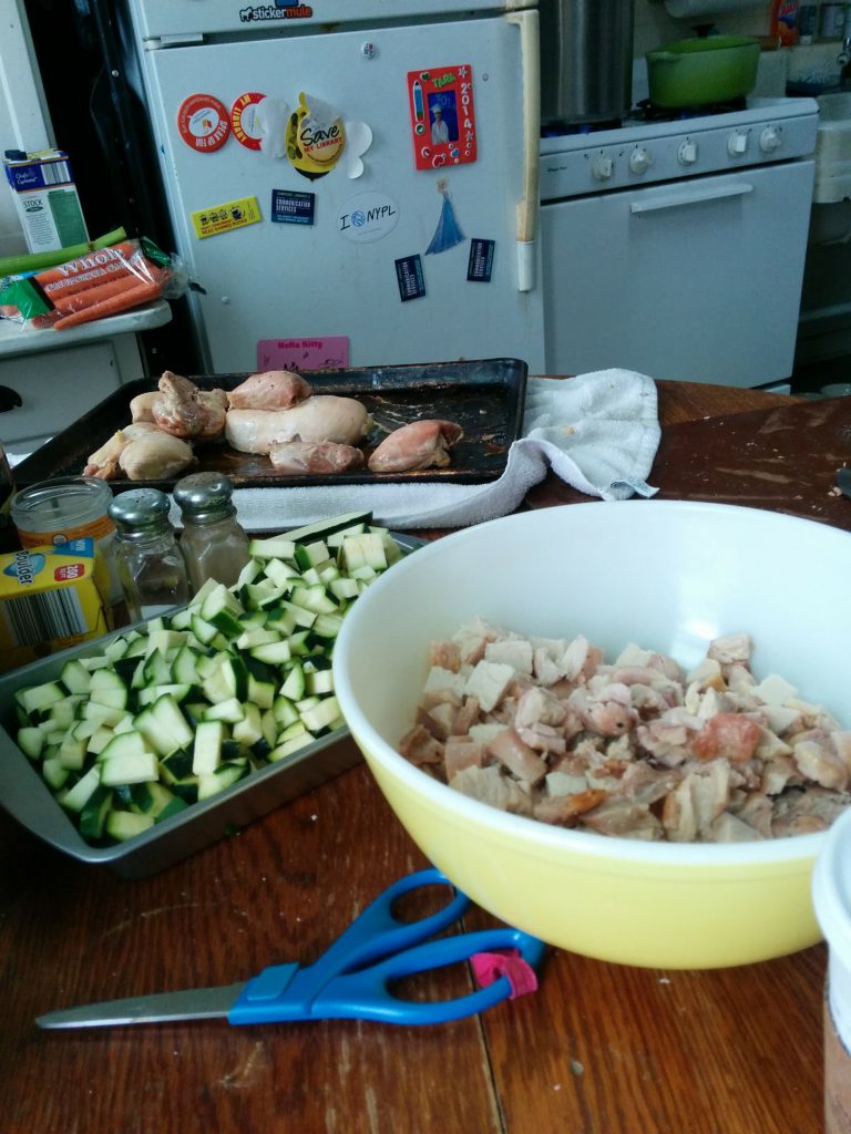 kitchen table, with pre chopped zuchinni and chicken being prepared